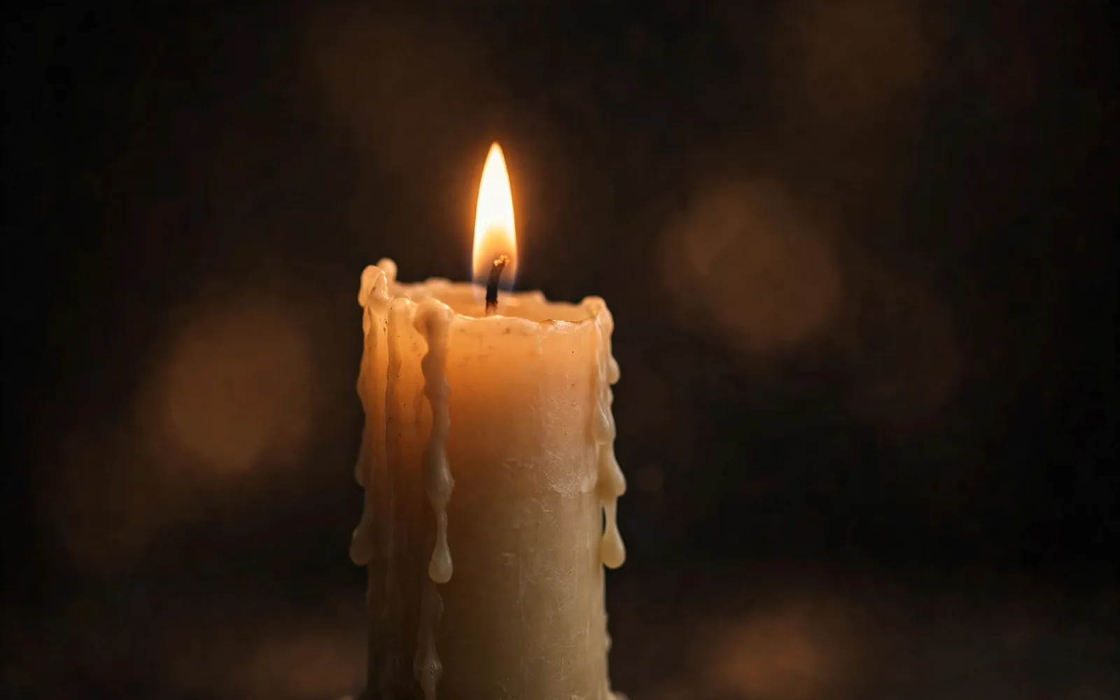 A single candle flame glowing in soft darkness